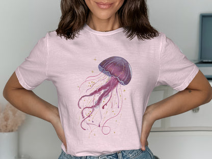 Pink t-shirt with a purple watercolor jellyfish illustration and gold accents.