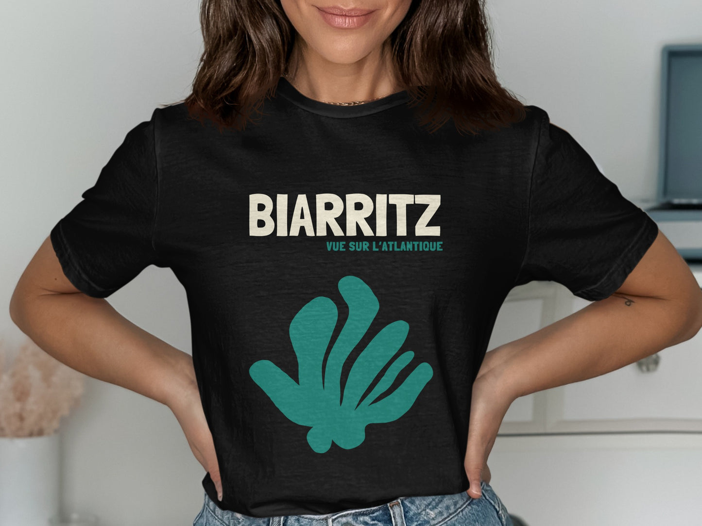 Black t-shirt with BIARRITZ and a teal abstract plant graphic.