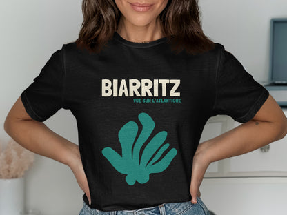 Black t-shirt with BIARRITZ and a teal abstract plant graphic.