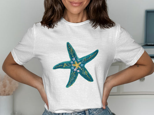 White t-shirt with a teal starfish design featuring small flowers and leaves.