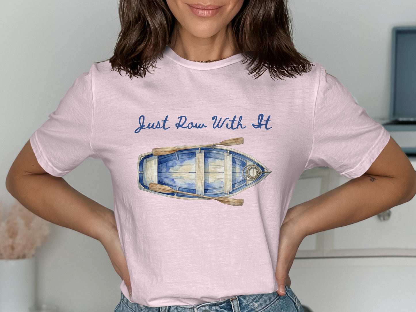 Pink t-shirt with a graphic of a blue rowboat and oars, text "Just Row With It".