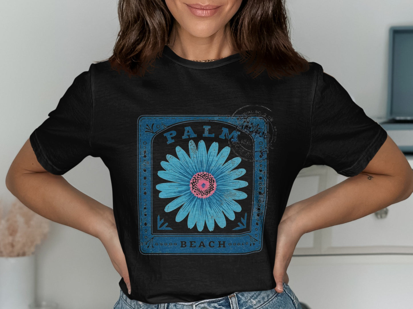 Black t-shirt with a blue square frame featuring a bright pink flower and "PALM BEACH" text.