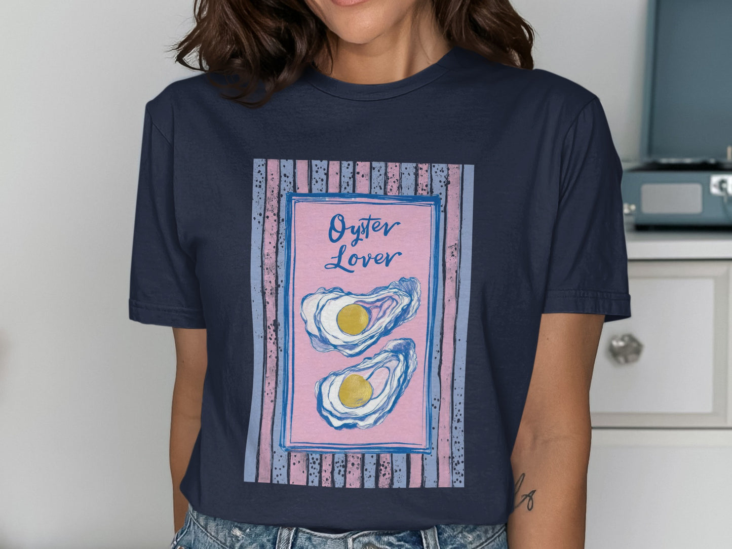 Navy t-shirt with pink and blue striped border and two oysters.