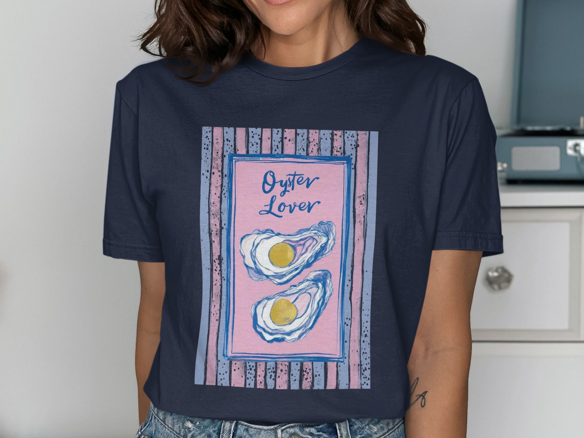 Navy t-shirt with pink and blue striped border and two oysters.