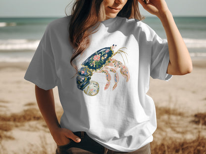 White t-shirt with a decorative crab illustration on a beach.