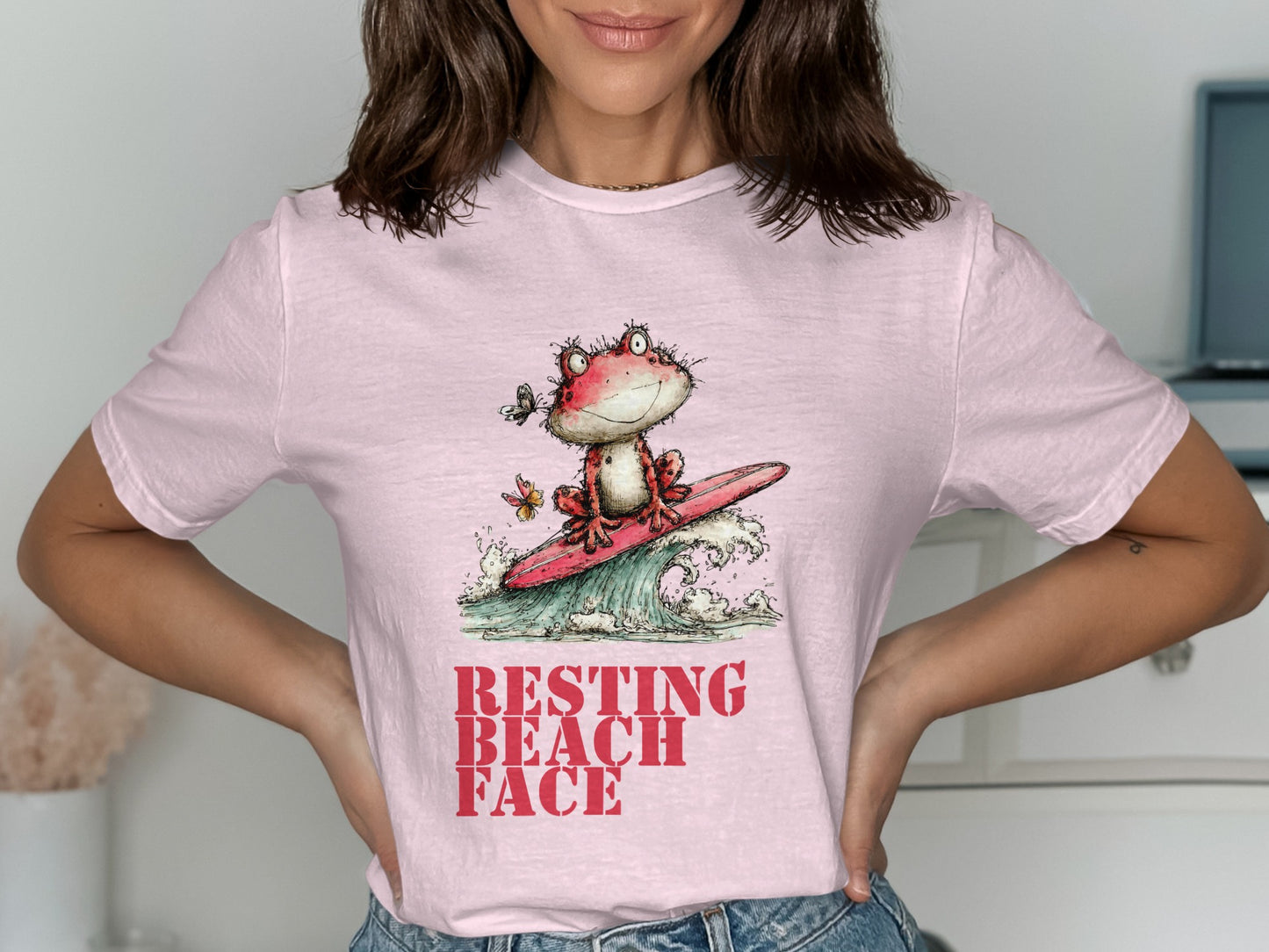 Pink t-shirt with cartoon frog surfing, text "RESTING BEACH FACE".
