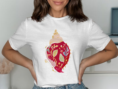 White t-shirt with a watercolor painting of a red shell with blue and gold floral accents.