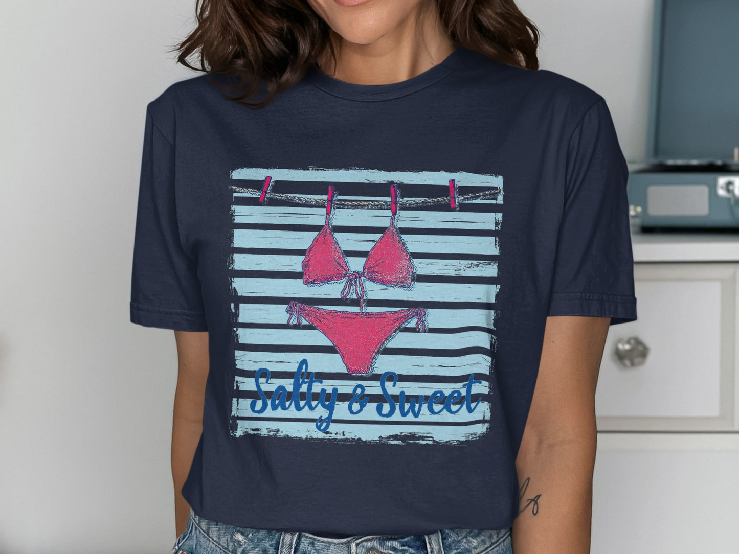 Navy t-shirt with a bikini and "Salty & Sweet" text hanging on a clothesline.