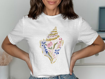 White t-shirt with a watercolor seashell illustration featuring pink and blue flowers.