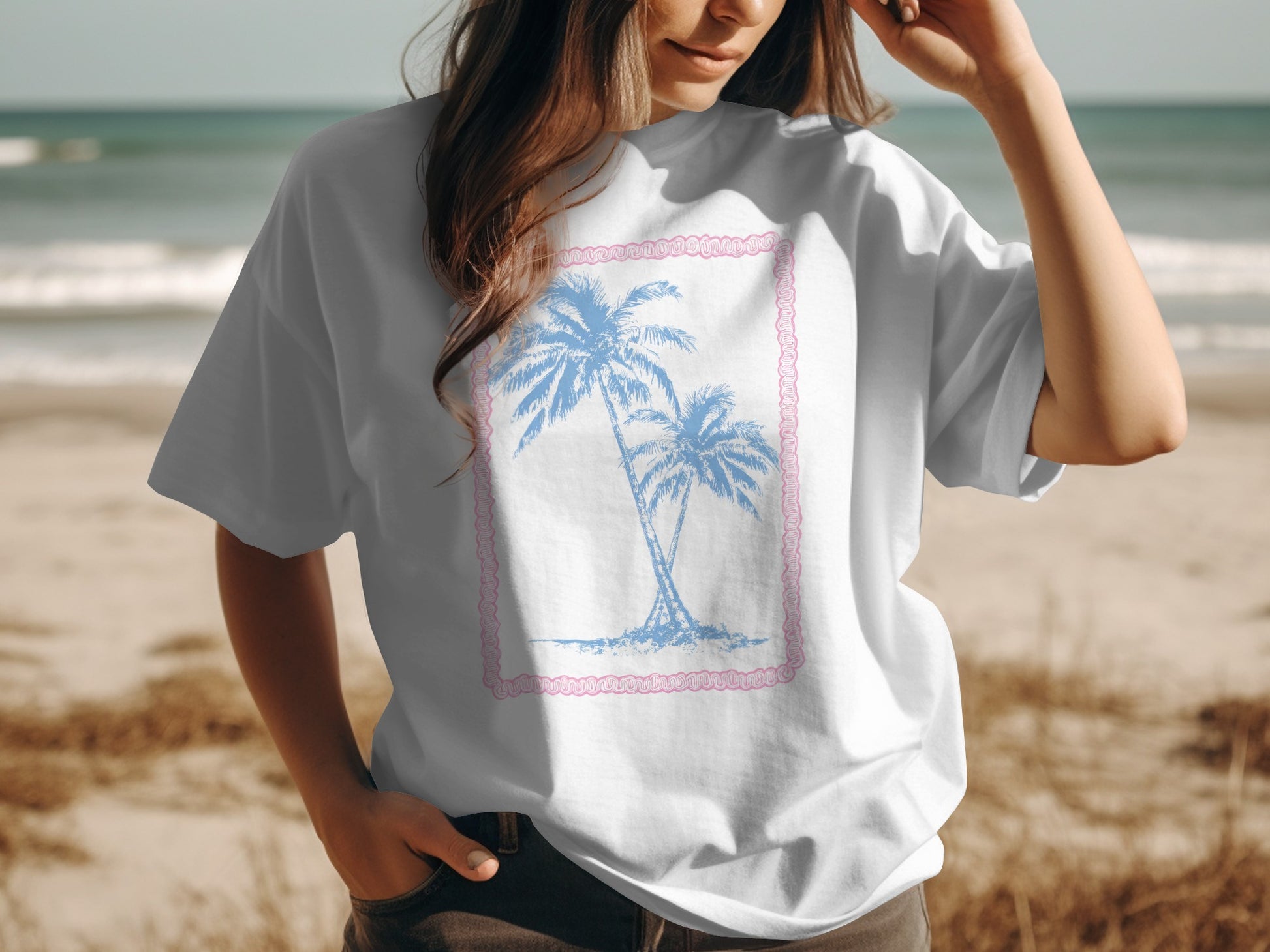 White t-shirt with a pink border and blue palm trees graphic.