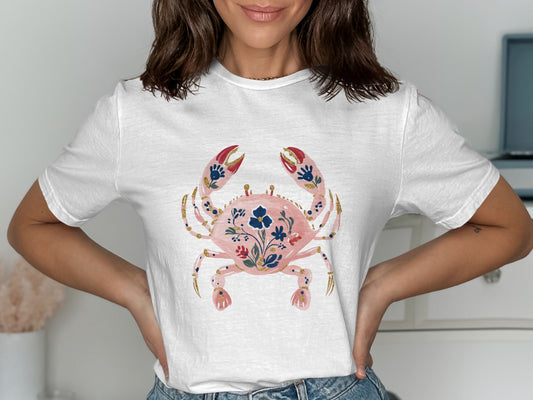 White t-shirt with a pink floral crab graphic and blue accents.