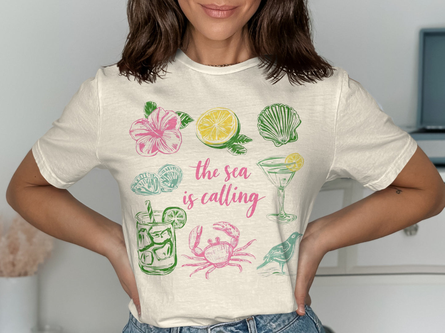 T-shirt with pink and green sea-themed illustrations and text "the sea is calling".