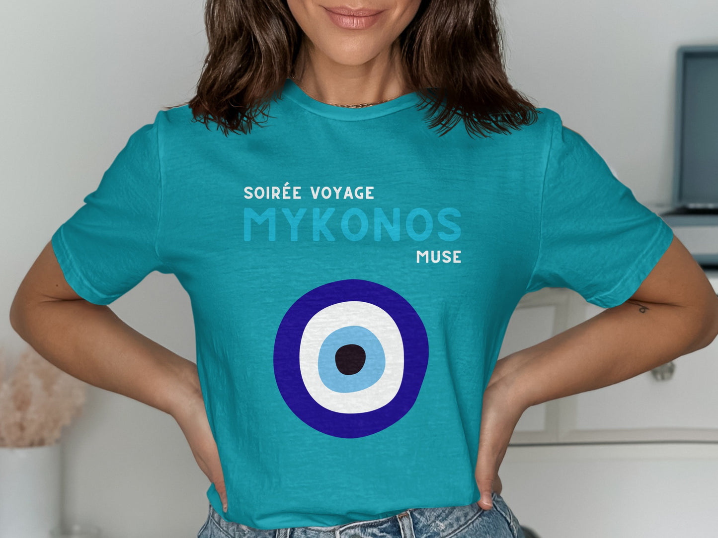 Turquoise t-shirt with "Soirée Voyage Mykonos" and evil eye design.