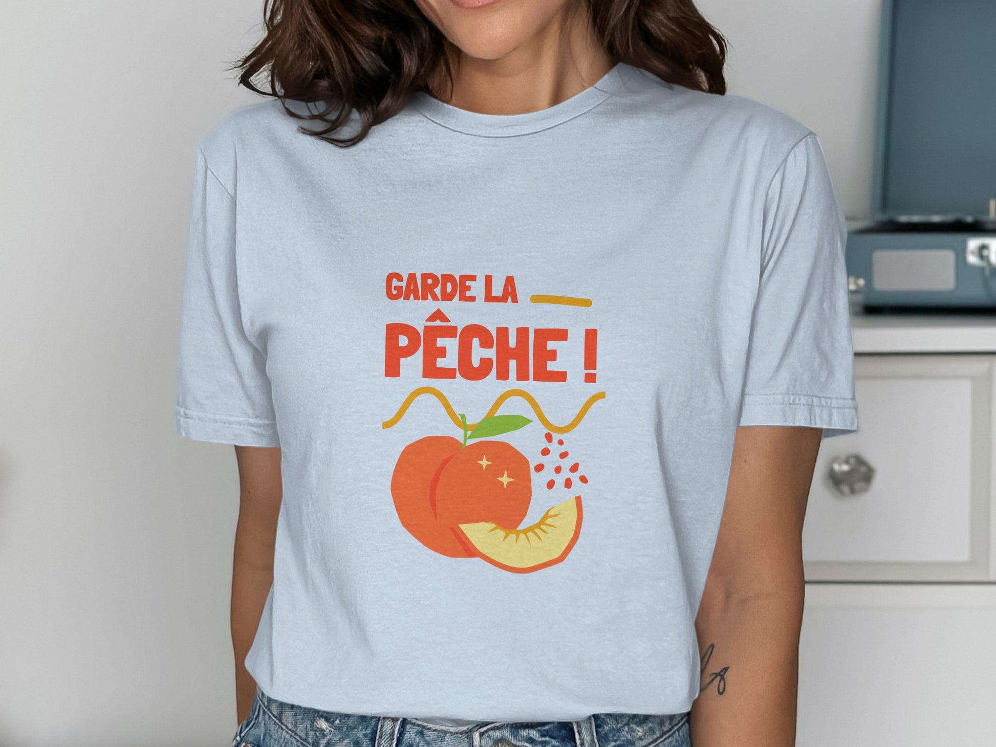 Light blue t-shirt with peach graphic and "Garde la pêche!" text.