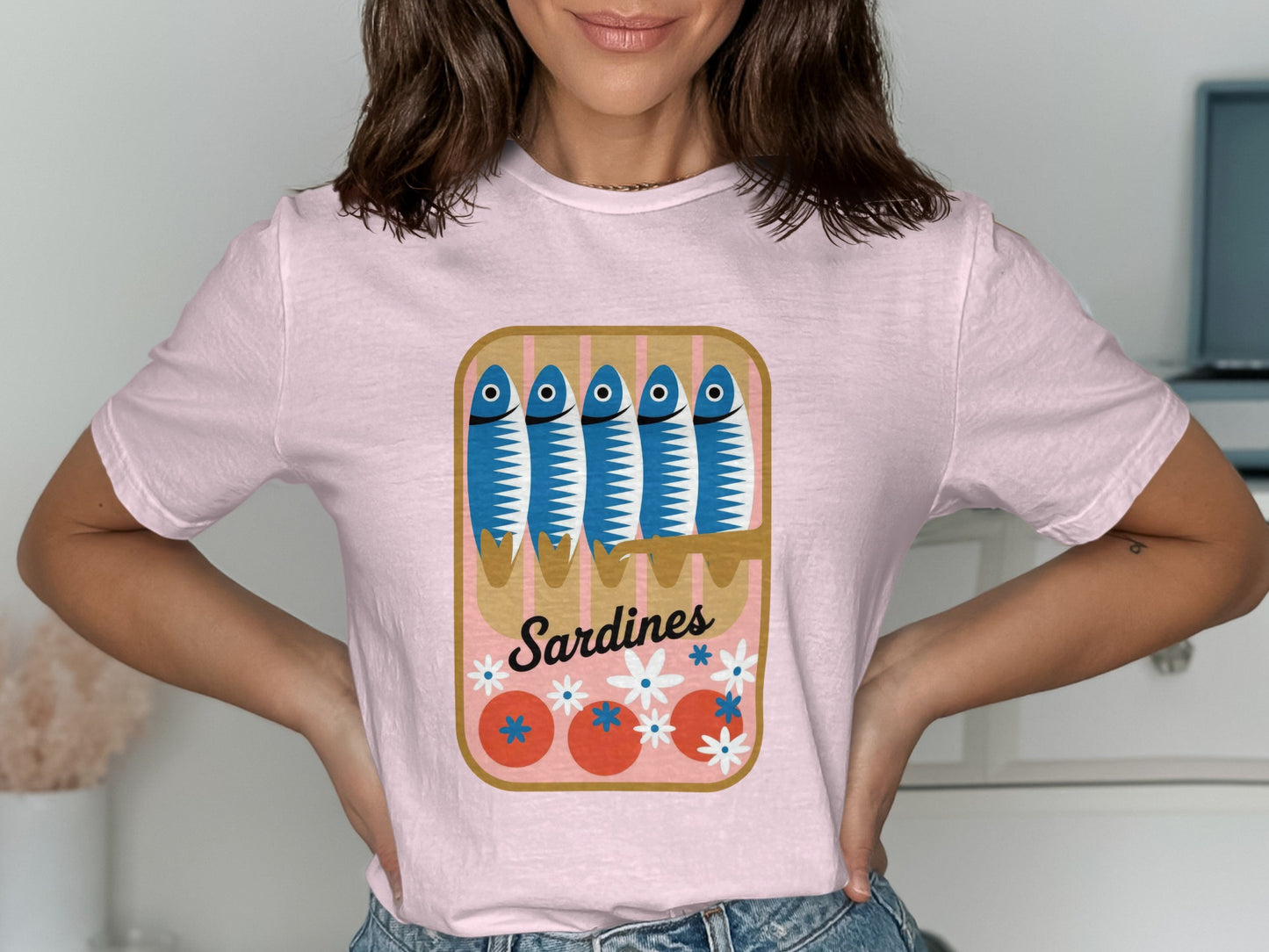 Pink t-shirt with a can of sardines, tomatoes, and flowers graphic.