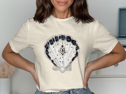 Cream t-shirt with ornate seashell design featuring blue and gold accents.