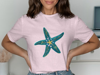 Pink t-shirt with teal starfish and floral design.