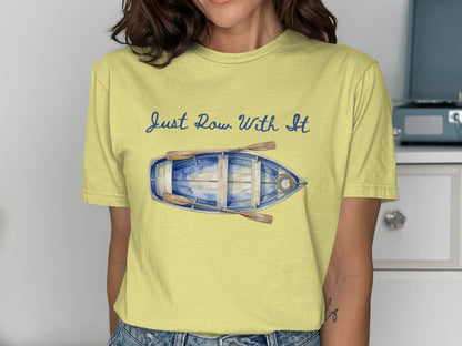 Yellow t-shirt with a watercolor painting of a rowboat and oars, and text "Just Row With It".
