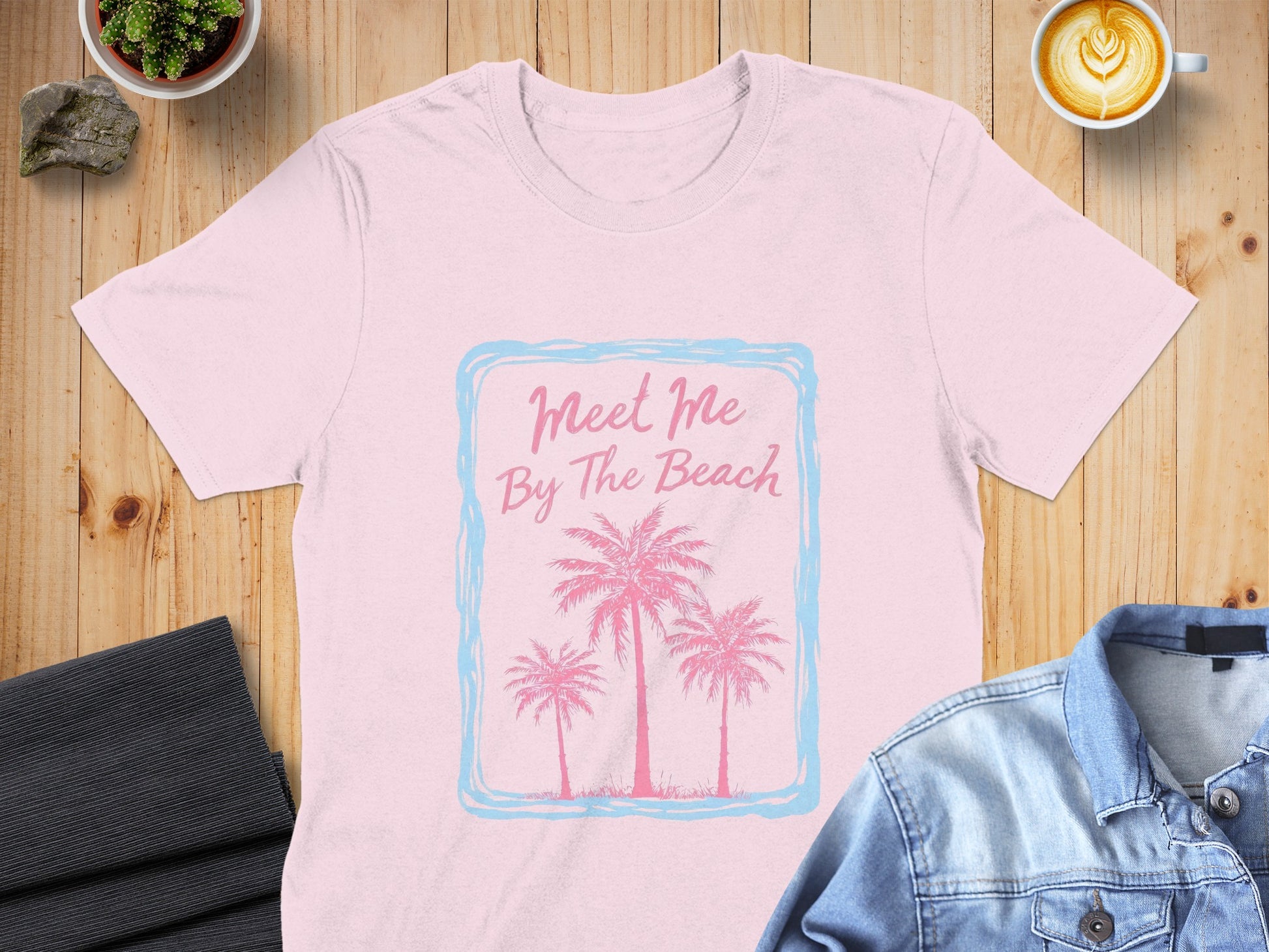Pink t-shirt with "Meet Me By The Beach" and palm trees design.