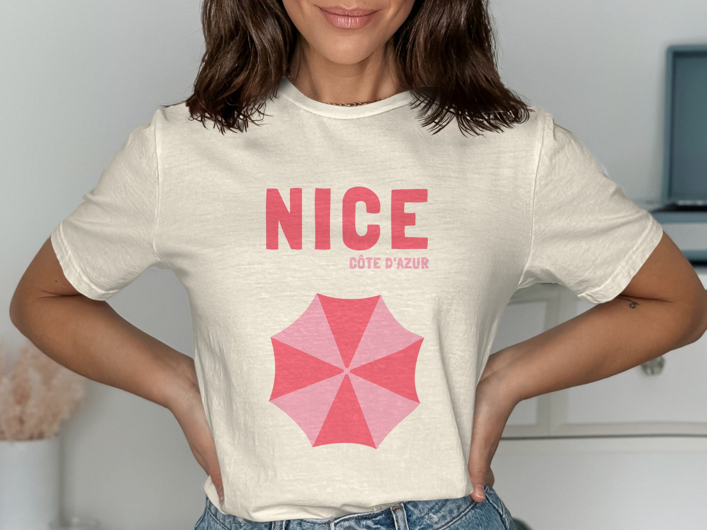 Cream t-shirt with "NICE CÔTE D'AZUR" and pink umbrella graphic.