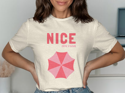 Cream t-shirt with "NICE CÔTE D'AZUR" and pink umbrella graphic.
