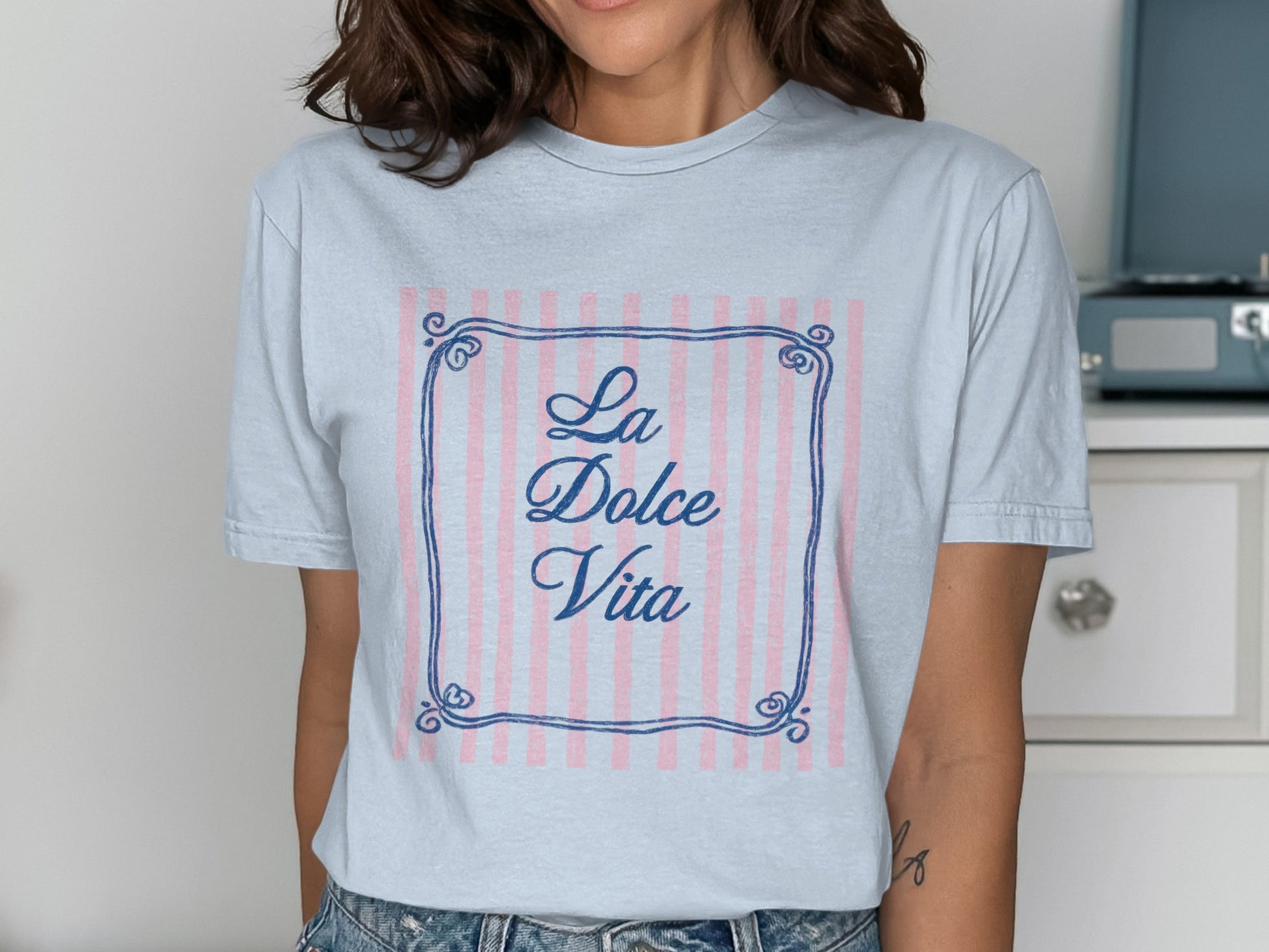 Light blue t-shirt with "La Dolce Vita" text inside a decorative frame.