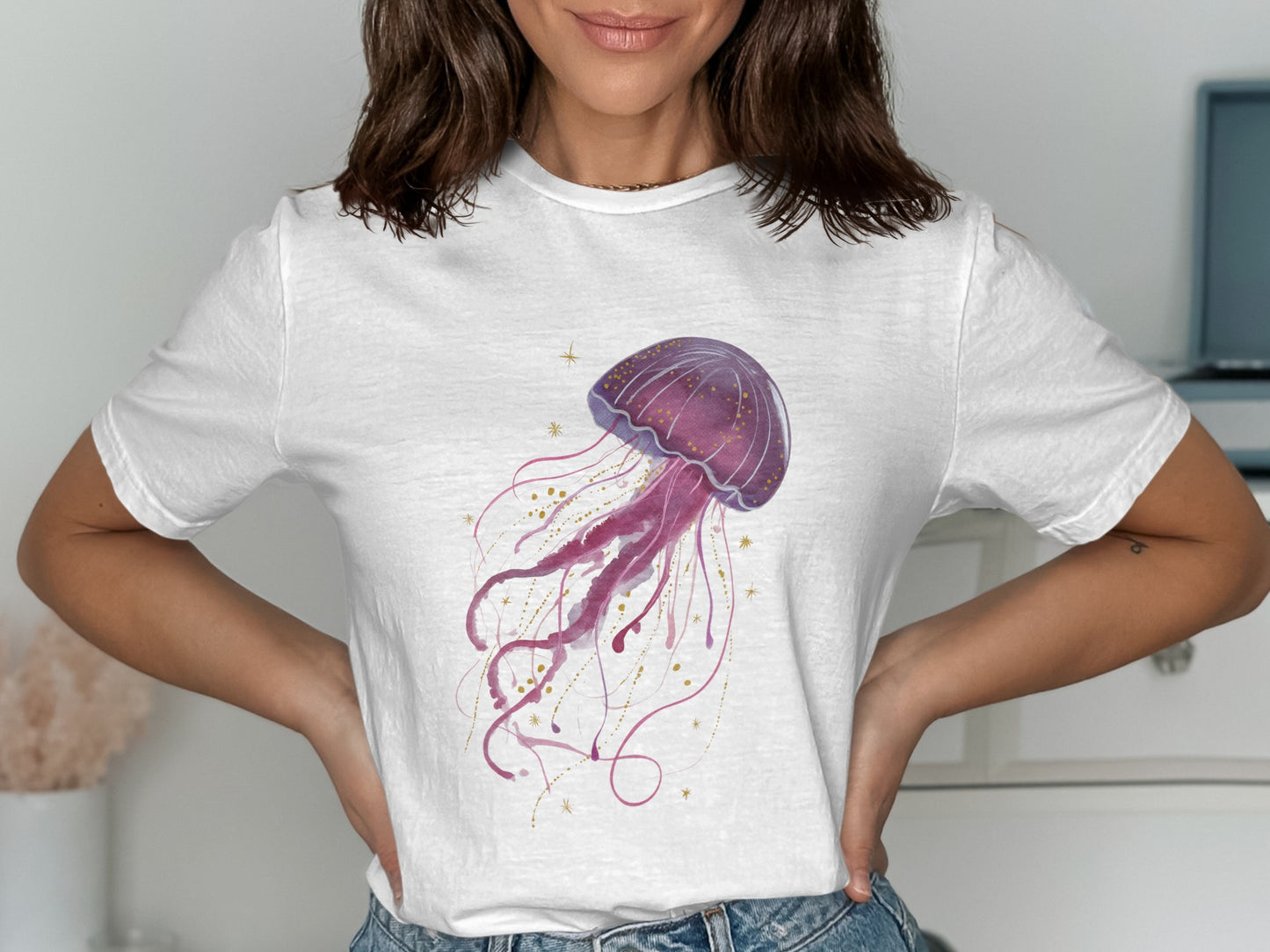 White t-shirt with a purple watercolor jellyfish and gold glitter accents.