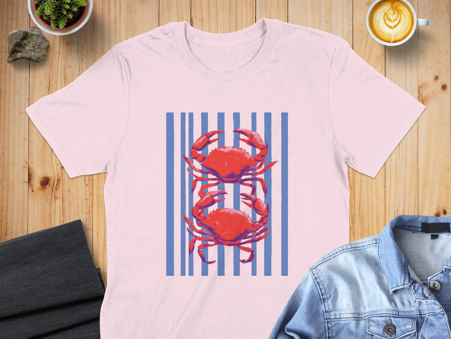 Pink t-shirt with two red crabs on a blue striped background.