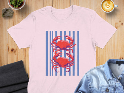 Pink t-shirt with two red crabs on a blue striped background.