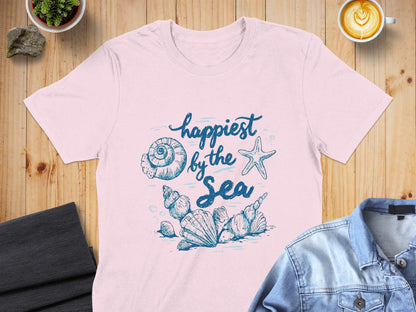 Pink t-shirt with blue watercolor "happiest by the sea" text and shell illustration.