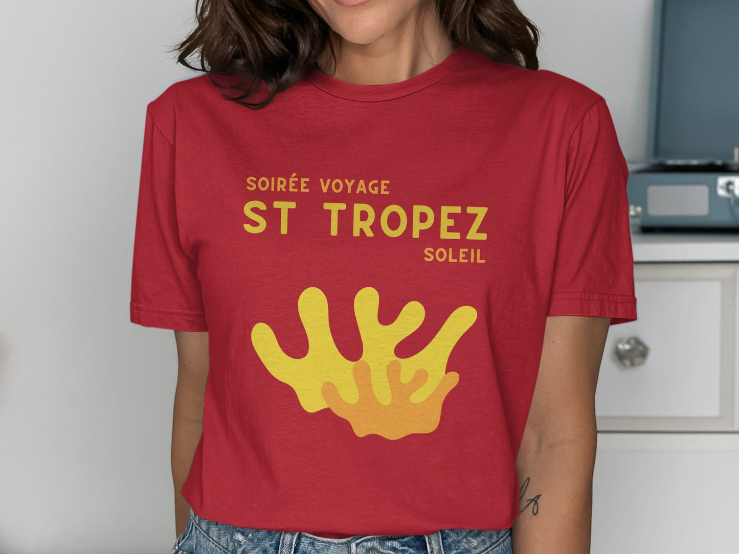 Red t-shirt with "Soirée Voyage St Tropez" and yellow coral graphic.