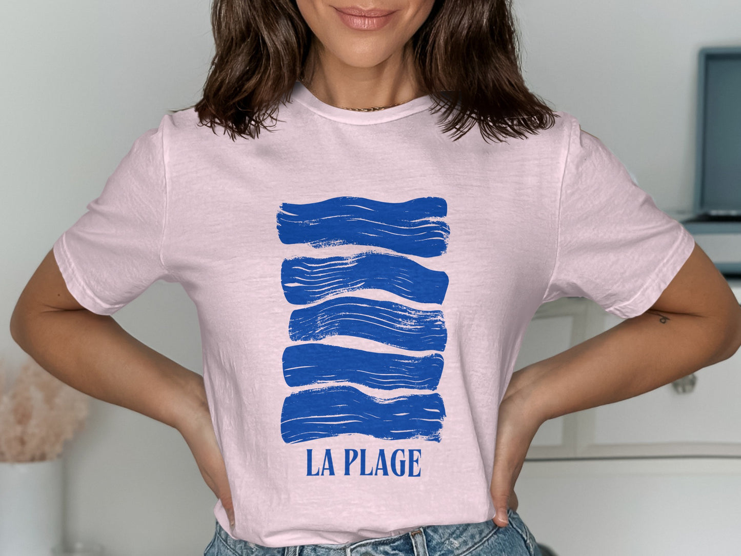 Pink t-shirt with abstract blue waves and "LA PLAGE" text.