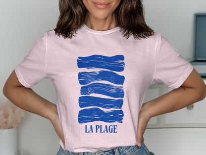 Pink t-shirt with abstract blue waves and "LA PLAGE" text.