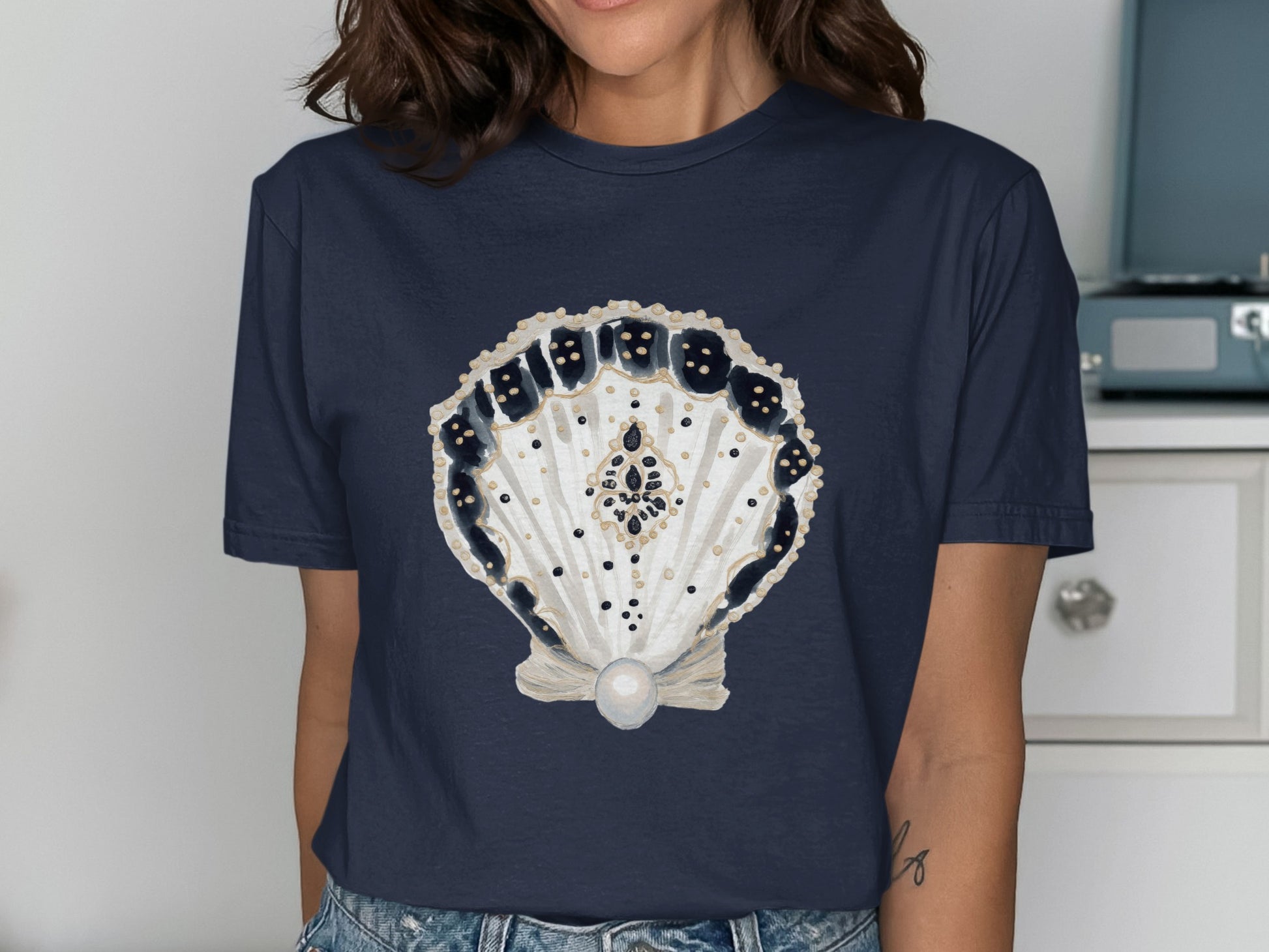 Navy t-shirt with a detailed seashell and pearl graphic.