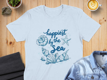 Light blue t-shirt with "happiest by the sea" and seashell graphic.