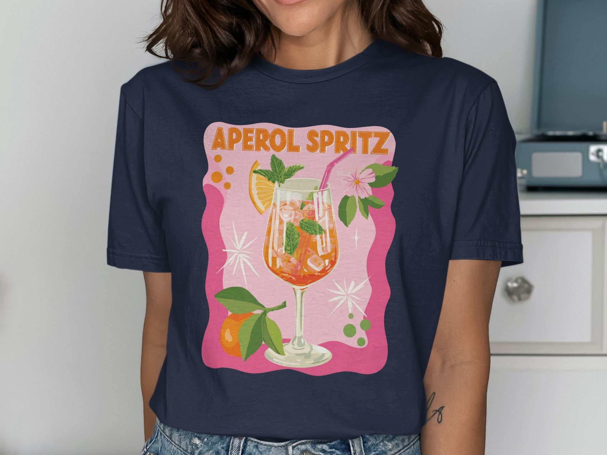 T-shirt with a graphic of an Aperol Spritz cocktail with orange slice and mint.