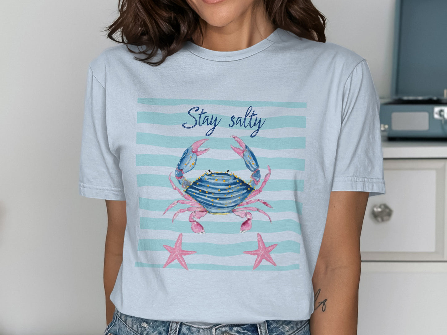 Light blue t-shirt with a cartoon crab and starfish, text "Stay salty".