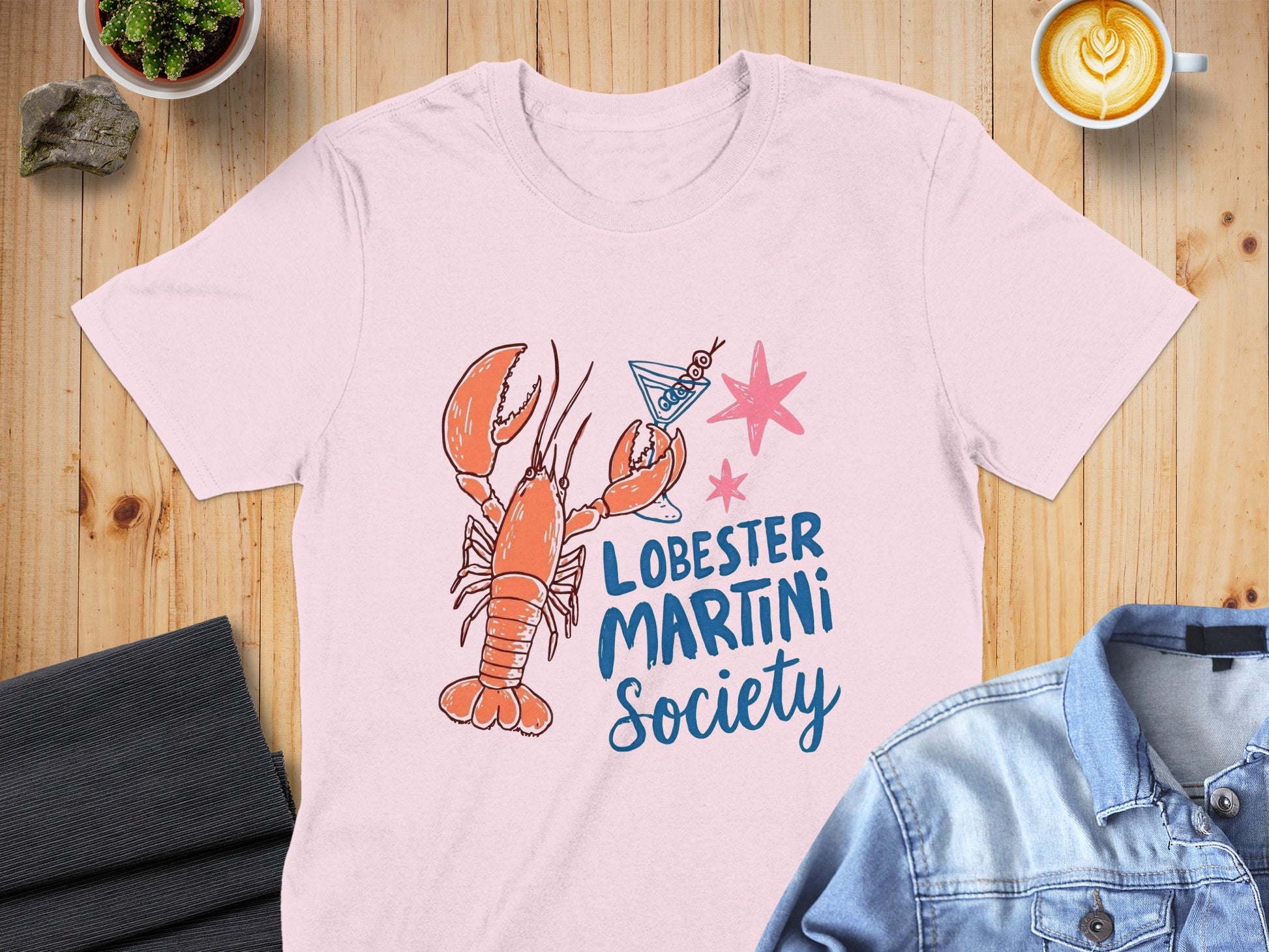 Pink t-shirt with a cartoon lobster holding a martini glass and "LOBESTER MARTINI Society" text.