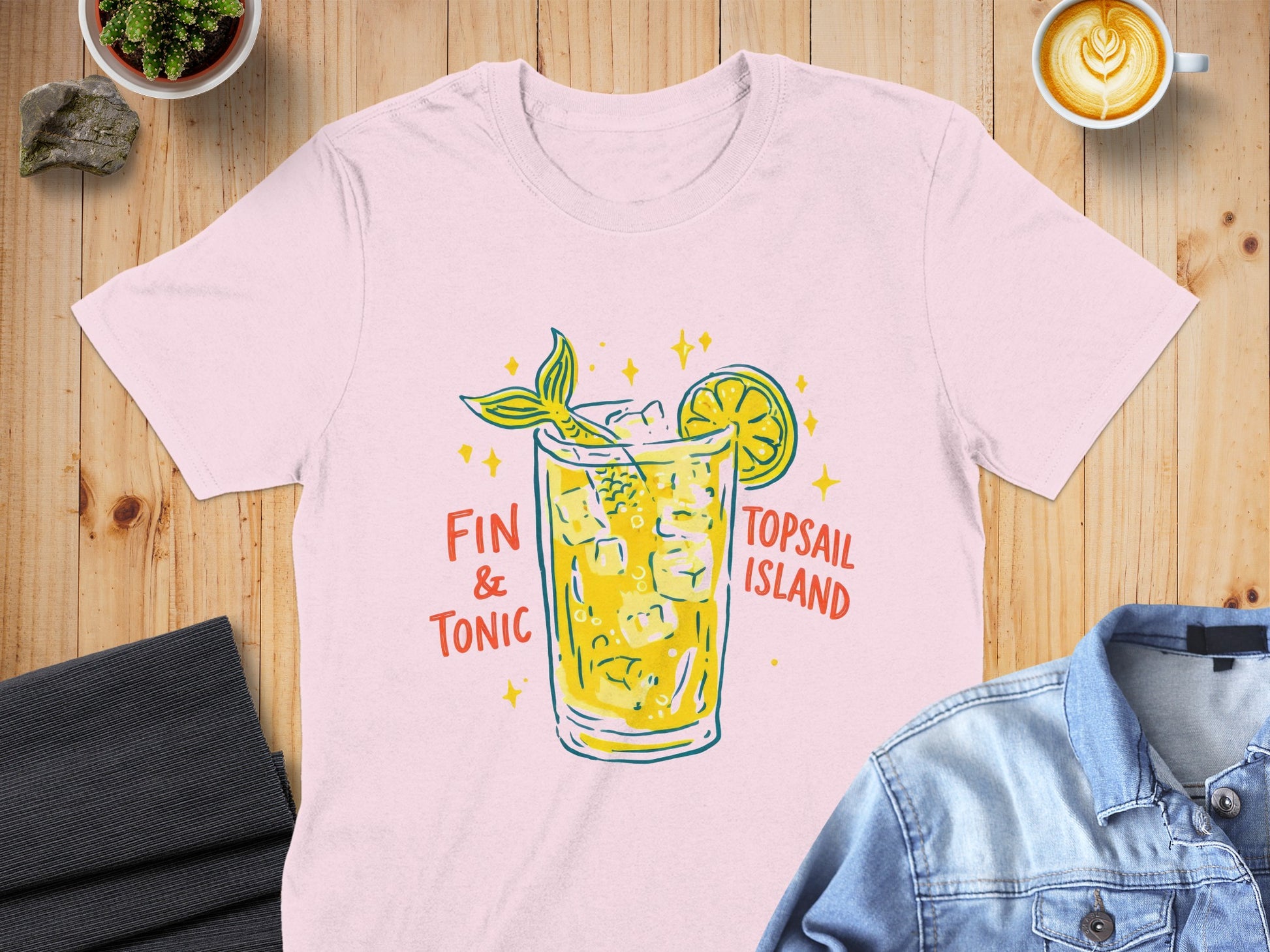 Pink t-shirt with a "Fin & Tonic" cocktail and mermaid tail graphic.