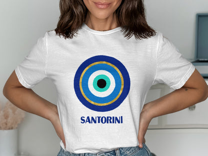 White t-shirt with blue and gold evil eye design and "SANTORINI" text.