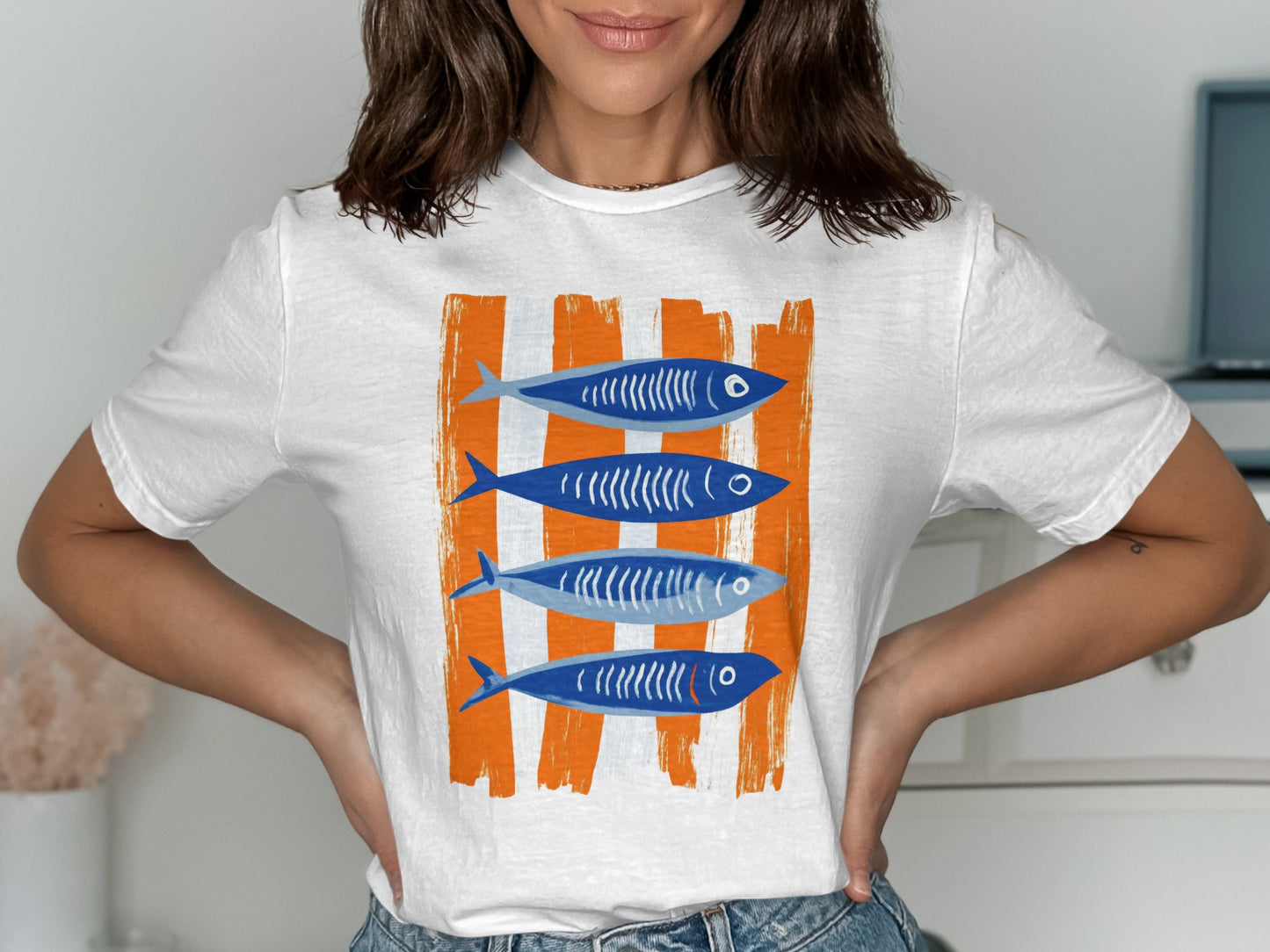 White t-shirt with four blue cartoon fish on orange stripes.