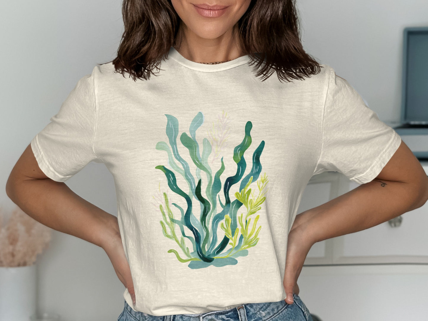 Cream t-shirt with a watercolor illustration of green seaweed and coral.