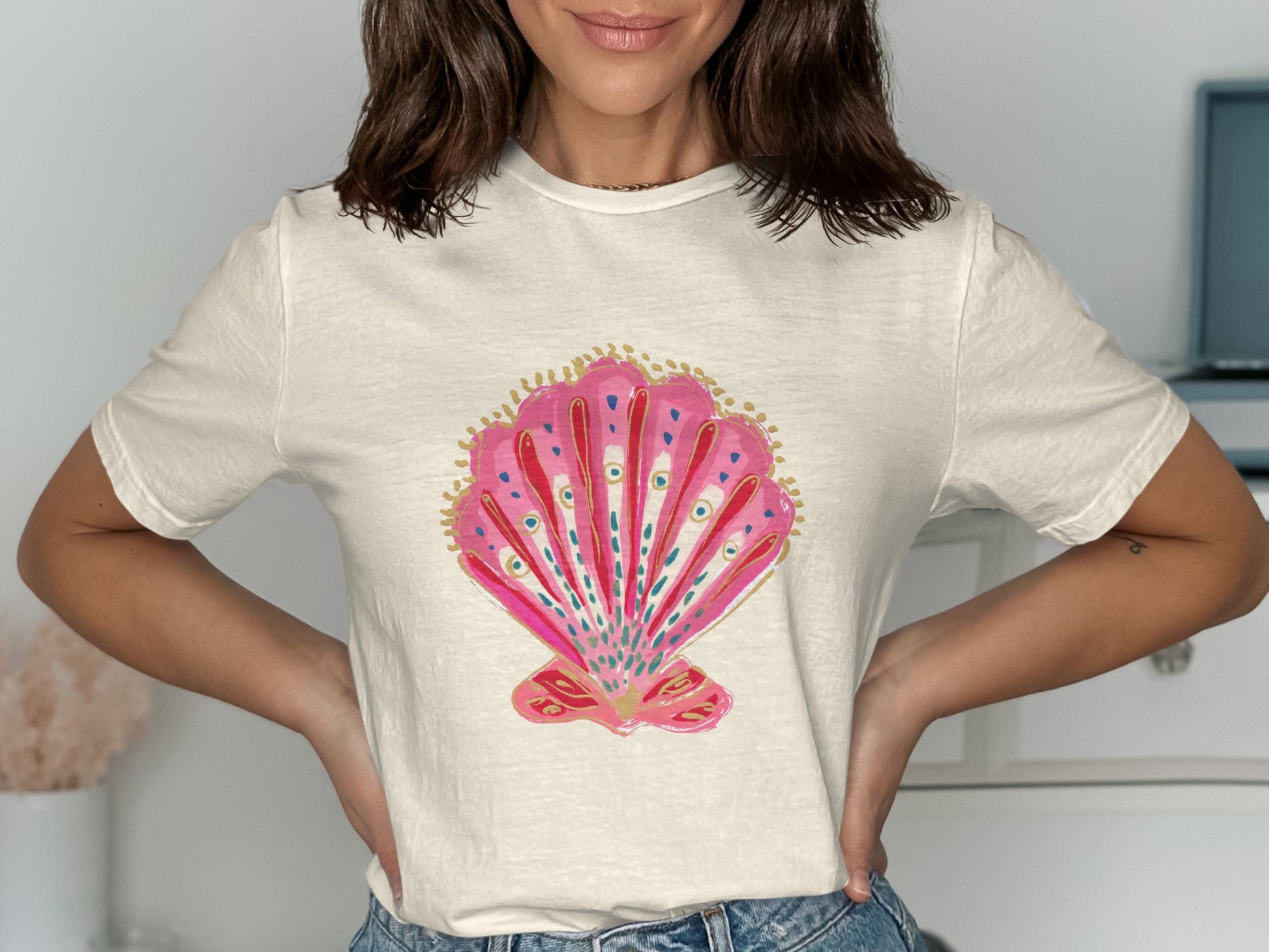 Cream t-shirt with a pink and gold watercolor seashell graphic.