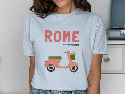 Pink scooter with basket of flowers and "ROME TOUS LES CHEMINS" text on light blue shirt.