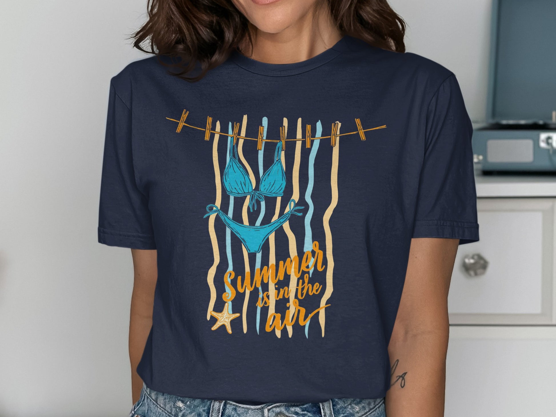Blue bikini and starfish hanging on clothesline with "Summer is in the air" text.