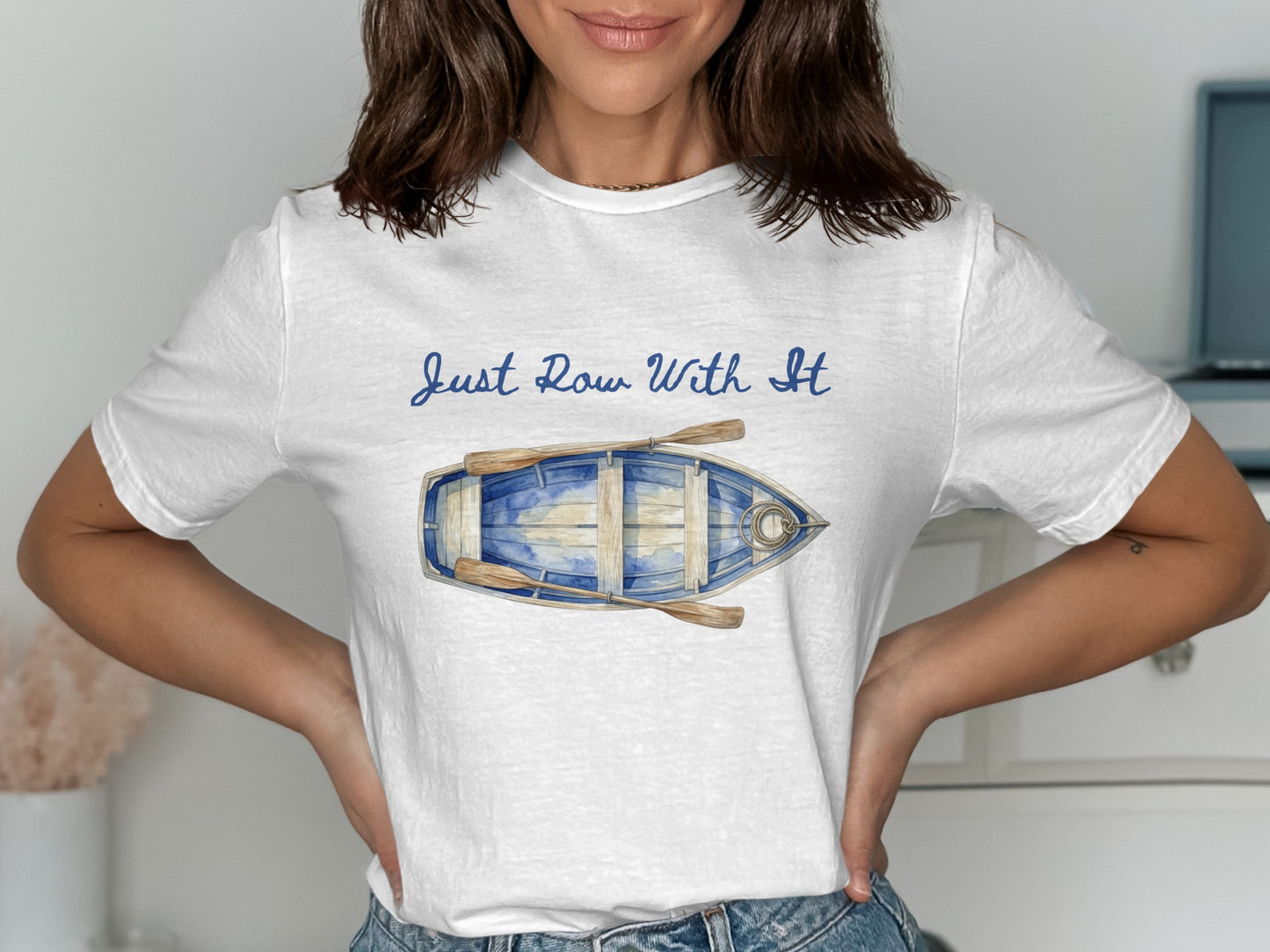 White t-shirt with blue watercolor rowboat graphic and text "Just Row With It."