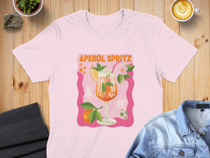 Pink t-shirt with Aperol Spritz graphic, featuring a cocktail and orange slices.