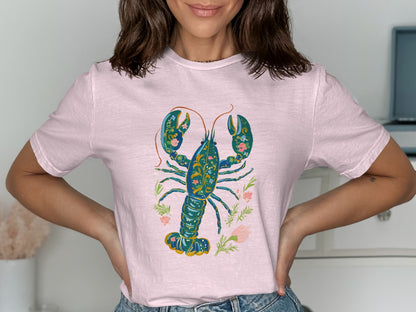 Pink t-shirt with a stylized blue and gold lobster surrounded by floral accents.