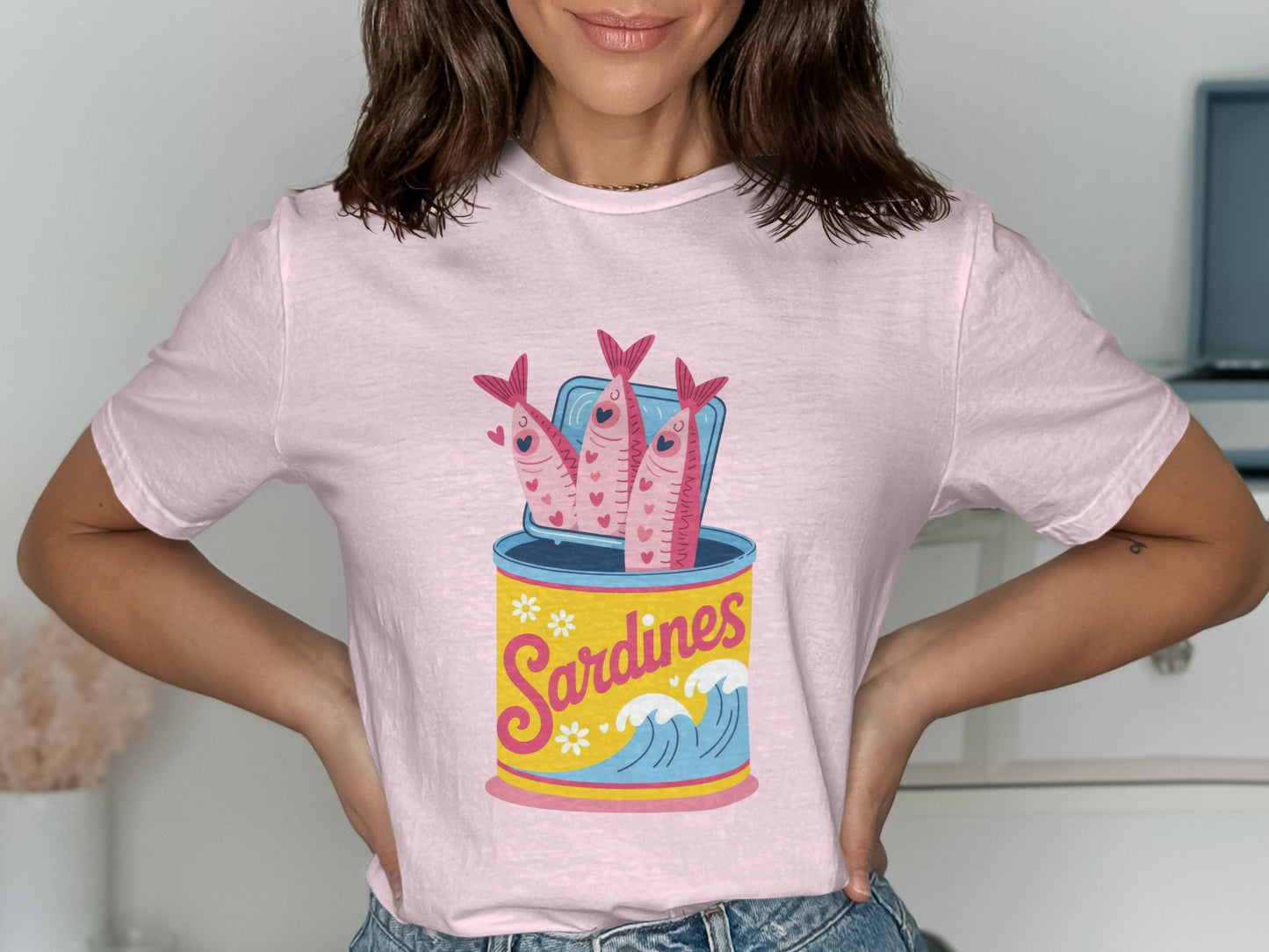 Pink t-shirt with cartoon sardines in a can with waves and flowers.