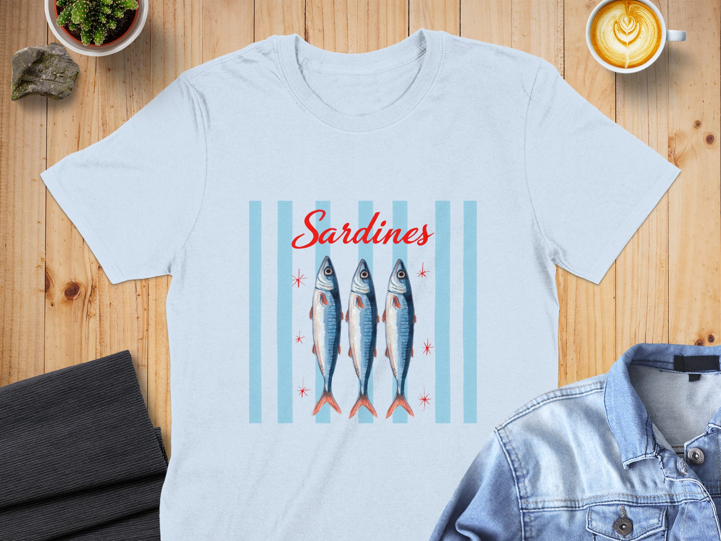 Light blue t-shirt with three sardines and red stars on blue stripes.